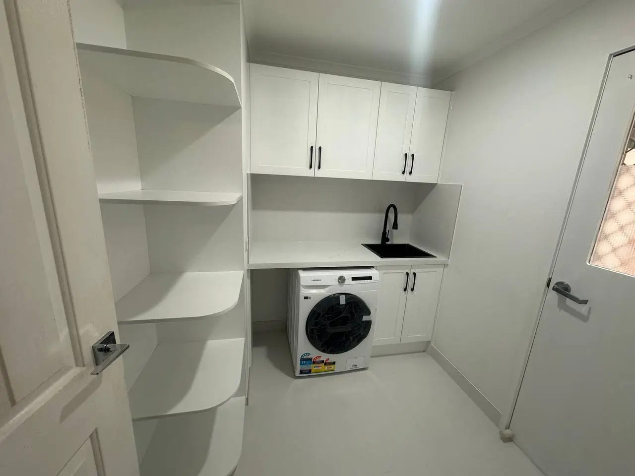 Laundry with cabinets in white colour